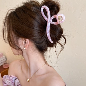 Detail of pink marble acrylic hair claw clip used in a French updo hairstyle on a model