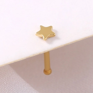 Macro shot of gold star-shaped stainless steel nose stud with smooth polished metal finish