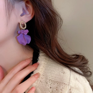 Close-up of a model wearing purple petal earrings with gold textured rings in a French style