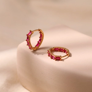 Close-up of gold-plated hoop earrings with rose red baguette-cut zircon stones