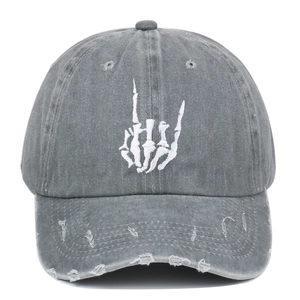Detailed shot of skull hand embroidery and distressed brim on gray washed cotton cap