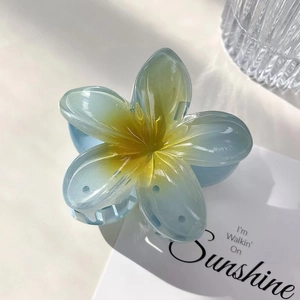 Detail view of a frangipani hair claw clip with blue and yellow gradient resin petals