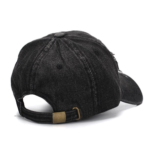 Detail view of washed black denim baseball cap with distressed texture and metal buckle