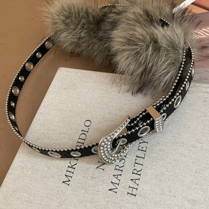 Détail d'une ceinture Y2K en cuir noir avec strass argentés et bordure en fourrure