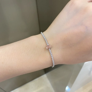 Detailed view of silver tennis bracelet with pink heart-shaped stone and zircon on wrist