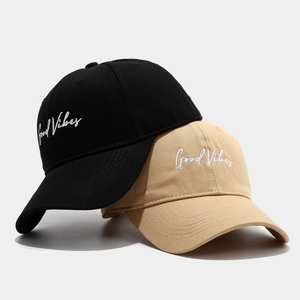 Black and beige cotton baseball caps with Good Vibes embroidery on a grey background