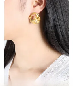 Macro detail of gold irregular lava texture earring on model with hollow geometric design