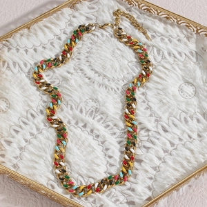 Detail of colorful enamel Cuban chain necklace with lobster clasp on gold display tray