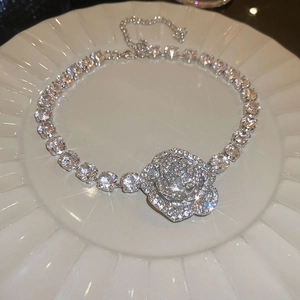 Close-up of sparkling rose pendant necklace with crystal zircons on a ceramic plate