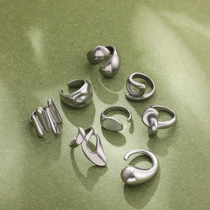 Detailed view of 8-piece silver liquid metal style rings on textured light green background