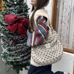 Plush beige tote bag with blue polka dots and brand label shown in a winter scene