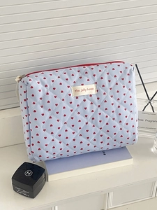 Detail of quilted light blue makeup bag with red heart pattern and zip closure