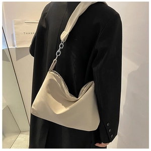 Detail of beige hobo bag showing wide shoulder strap and silver metal chain link