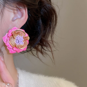 Gros plan d'une boucle d'oreille fleur rose avec centre violet pour un look rétro