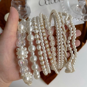 Detail showing a variety of elegant white pearl headbands with golden alloy frames