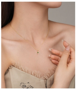 Detail of s925 silver necklace with green gemstone heart pendant on a female model