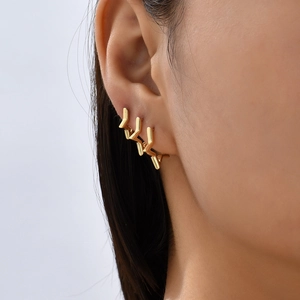 Close-up of triple layered gold geometric lightning bolt stud earrings on model ear