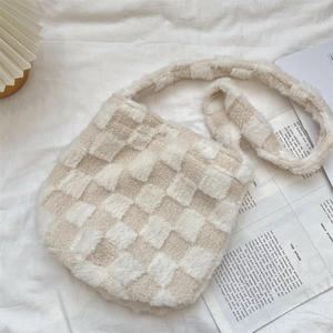 Detail of plush checkerboard bucket bag on white fabric with cozy home decor accents
