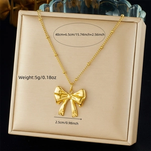 Detailed size specifications for the gold bow necklace in a beige jewelry display box