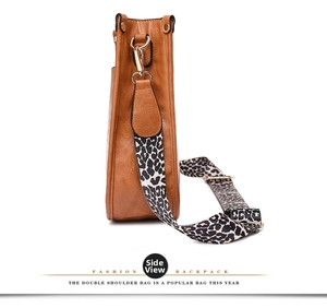 Side view of a brown faux leather tote bag with a leopard print wide fabric strap