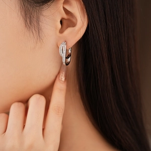 Detail view of double-layer crossover silver earrings with inlaid cubic zirconia on model