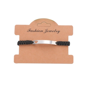 Detail of adjustable black woven cord bracelet with curved silver heart cutout charm on card
