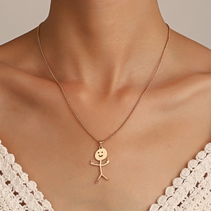 Detalle de un collar dorado con un divertido colgante de monigote con gesto audaz
