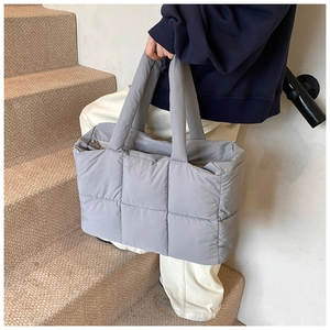 Detail of grey down quilted tote bag showing square stitching and puffer fabric texture