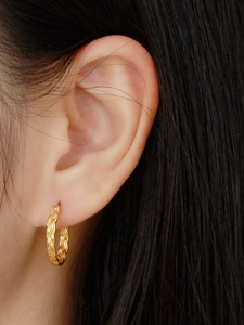 Close-up of a gold s925 silver woven chain link hoop earring worn on a model ear