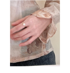 Close-up of a minimalist golden pearl ring worn on a finger for a vintage elegant look