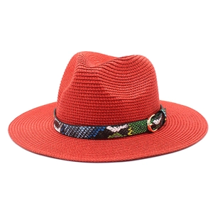 Detail of red straw Fedora hat featuring colorful snakeskin band with golden buckle