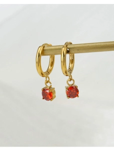 Detailed view of gold hoop earrings featuring a brilliant round red zircon stone pendant
