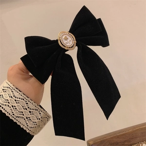 Detail of vintage black velvet bow hair clip with pearl rose cameo and gold frame