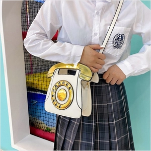 Detail of creative vintage white telephone bag with golden dial and metallic handle detail