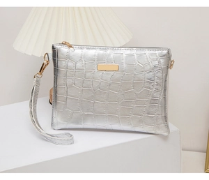 Macro shot of silver crocodile texture clutch bag with gold zipper and wrist strap