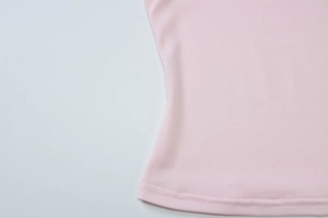 Détail du haut rose ajusté montrant la texture lisse du tissu et les coutures de l'ourlet