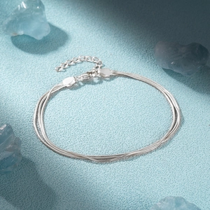 Detailed view of 925 sterling silver triple layer snake bone chain bracelet on blue crystals