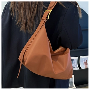 Detailed view of caramel leather hobo bag with gold buckle on a model's shoulder