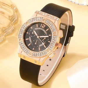 Detail of rose gold rhinestone watch with black leather strap and chronograph style dial