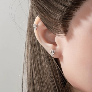 Silver textured harp-shaped stud earrings shown on model for stylish ear cartilage piercing