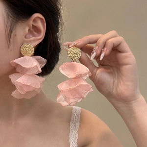 Macro detail of elegant pink chiffon fabric petals and golden textured metal ear studs
