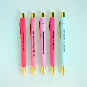 Close-up of five pink and white ballpoint pens with gold clips and motivational quotes