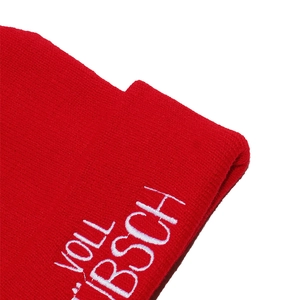 Macro shot of red knit beanie featuring white embroidery and detailed ribbed texture