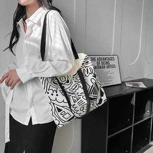 Detailed view of large canvas tote with black and white graffiti print and webbed handles