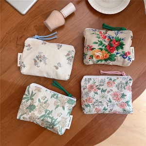 Assorted floral canvas pouches with zippers and woven tags on a wooden desk