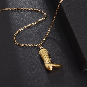 Close-up of golden cowboy boot pendant with detailed floral relief on textured background