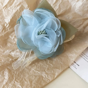Détail de la pince à cheveux fleur en maille bleu clair avec feuilles vertes et acrylique