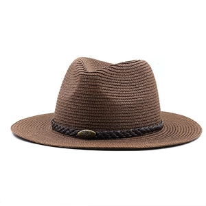 Detail of dark brown fedora straw hat with a vintage bronze bull emblem on woven band