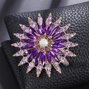 Detailed macro view of a sunburst flower brooch with purple gemstones and gold-plated alloy