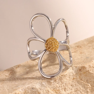 Macro detail of a silver flower ring with a gold textured center on a mineral stone